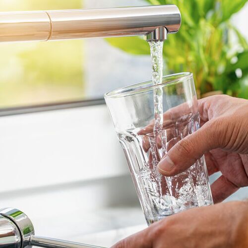 Closeup shot of a man pouring a glass of fresh water from a kitc